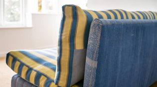  Blue sofa with stripy yellow and blue cushions facing a window.
